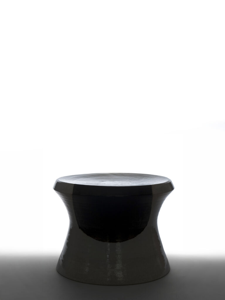 Silhouette rétroéclairée du tabouret Georgio en céramique noire et blanche, mettant en valeur sa forme évasée et son motif circulaire